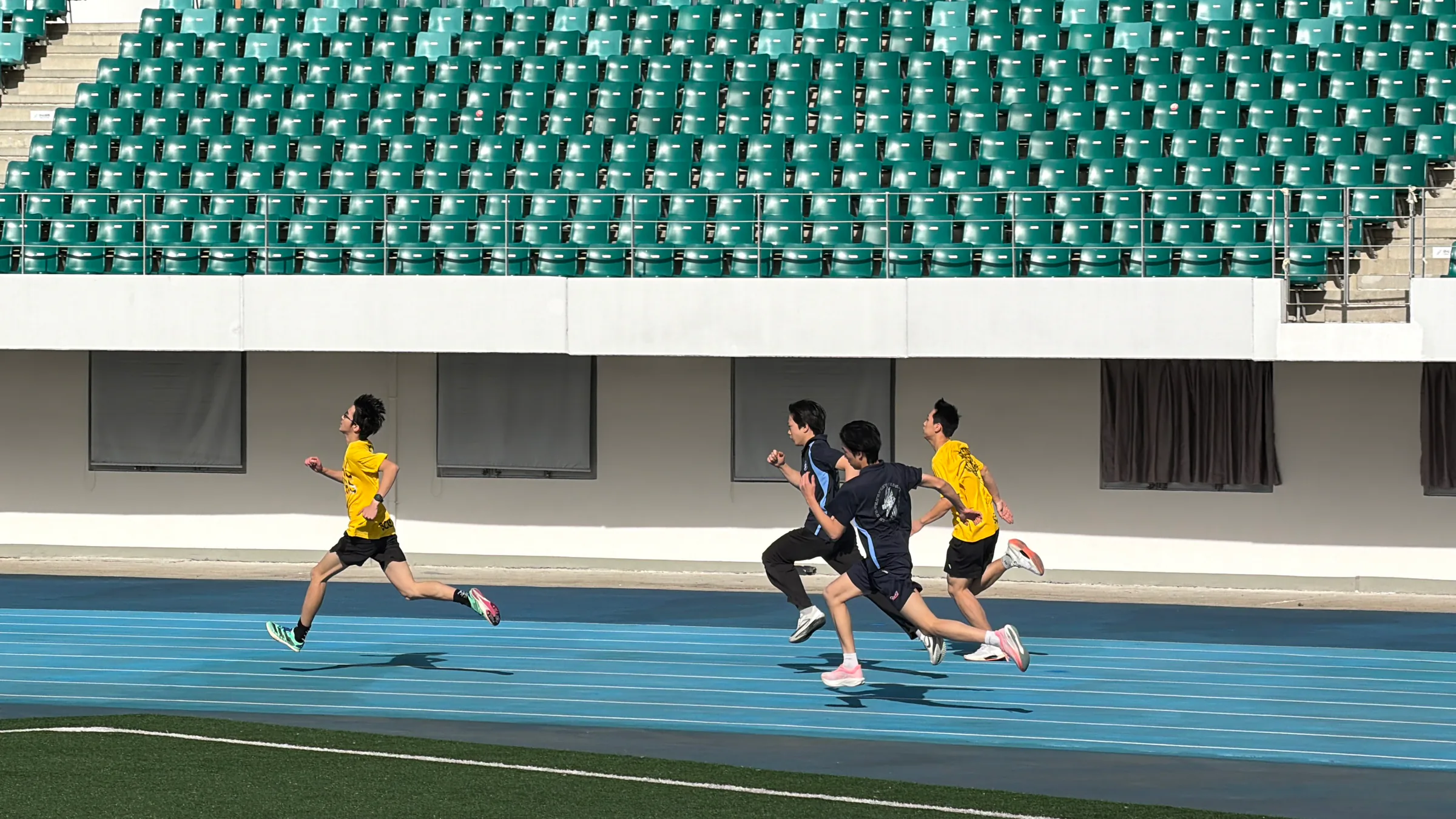 Students running a sprint event on a blue athletics track